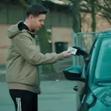 Ung fyr modtager penge fra en mand i en bil